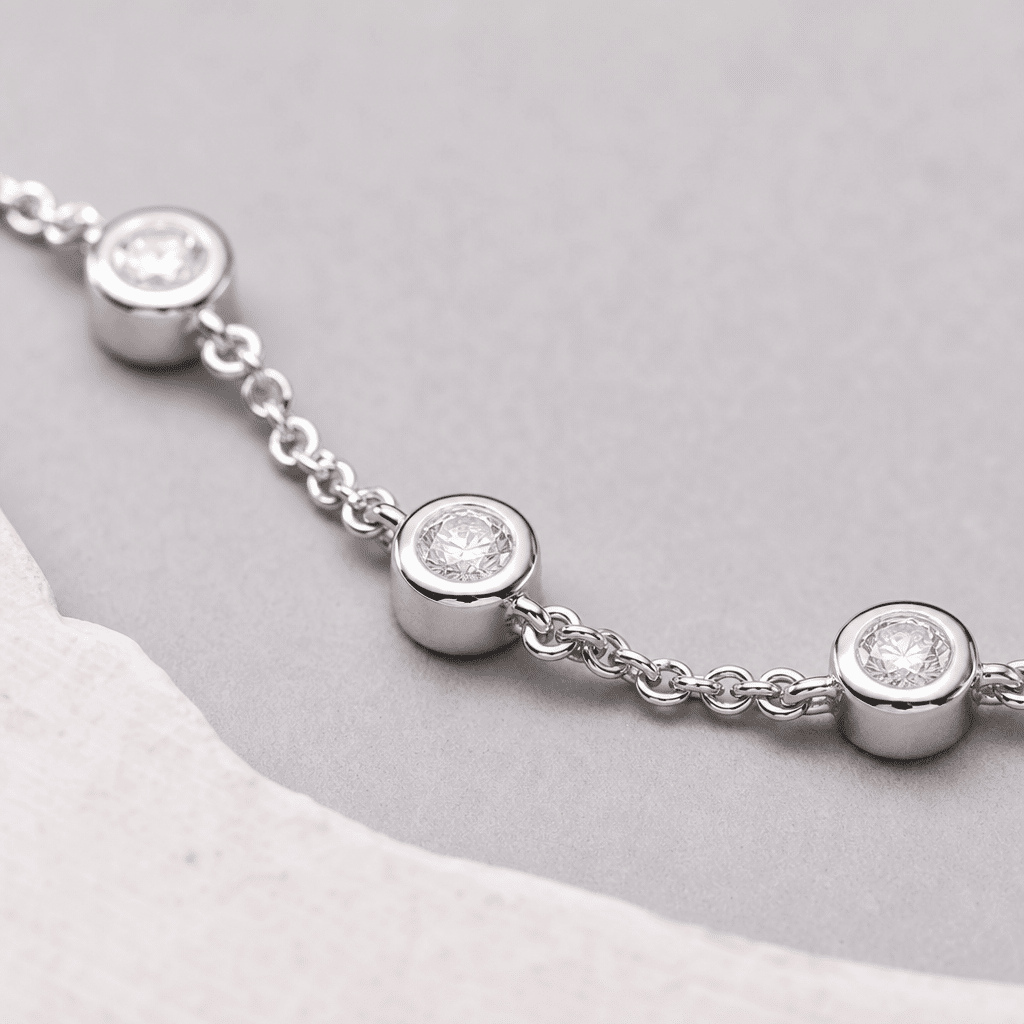 Close-up of a lab-grown diamond station bracelet showing the bezel-set stone stations and the chain link connection points between them.