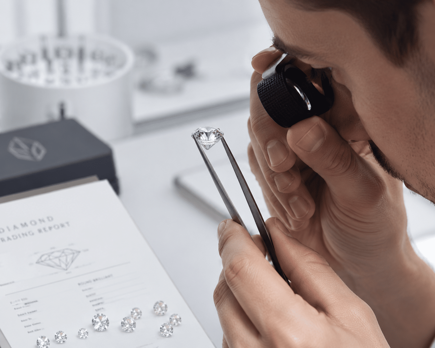 A jeweler inspecting a loose diamond with a loupe to read the laser inscription on the girdle