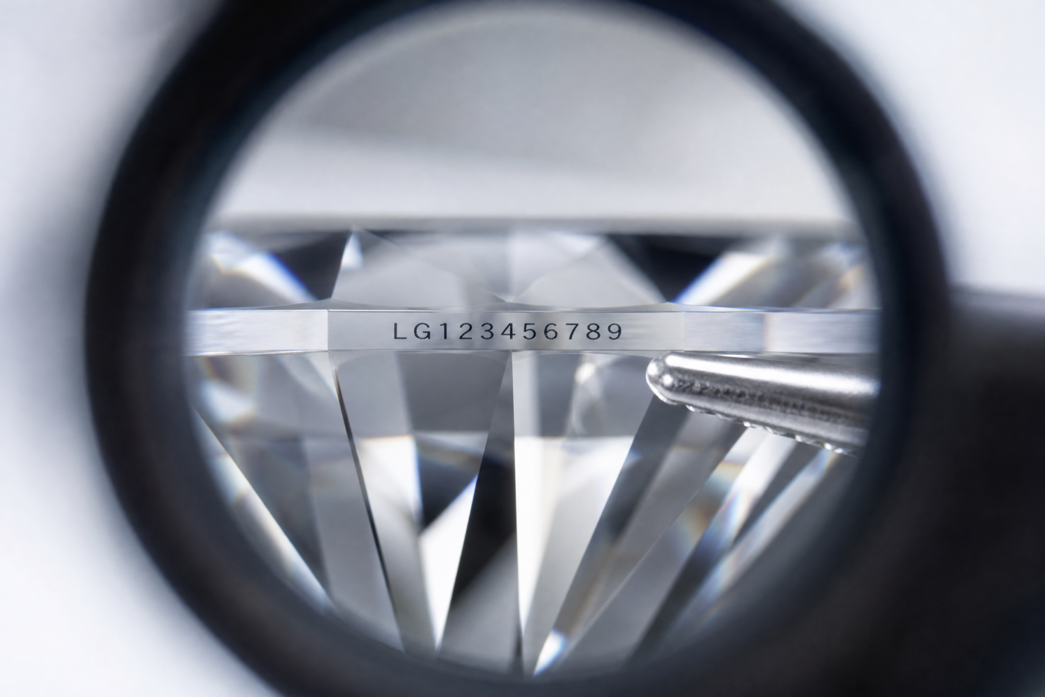 Close-up microscope view of a lab-grown diamond girdle showing a laser-inscribed report number, with the characters centered and readable against the polished surface.